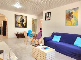 Open plan living and dining room with blue sofa, glass table and modern decor Pedasí Panama