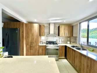 Contemporary kitchen with wood cabinetry, quartz counters, gas stove in PH Mosaic Panama Pacifico