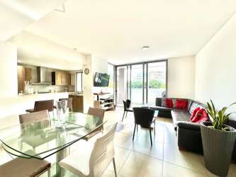 Open-plan living and dining area with modern kitchen, large windows at PH Mosaic Panama Pacifico