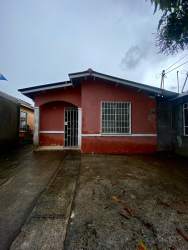 Small single-story red house with barred windows and driveway Panama Oeste