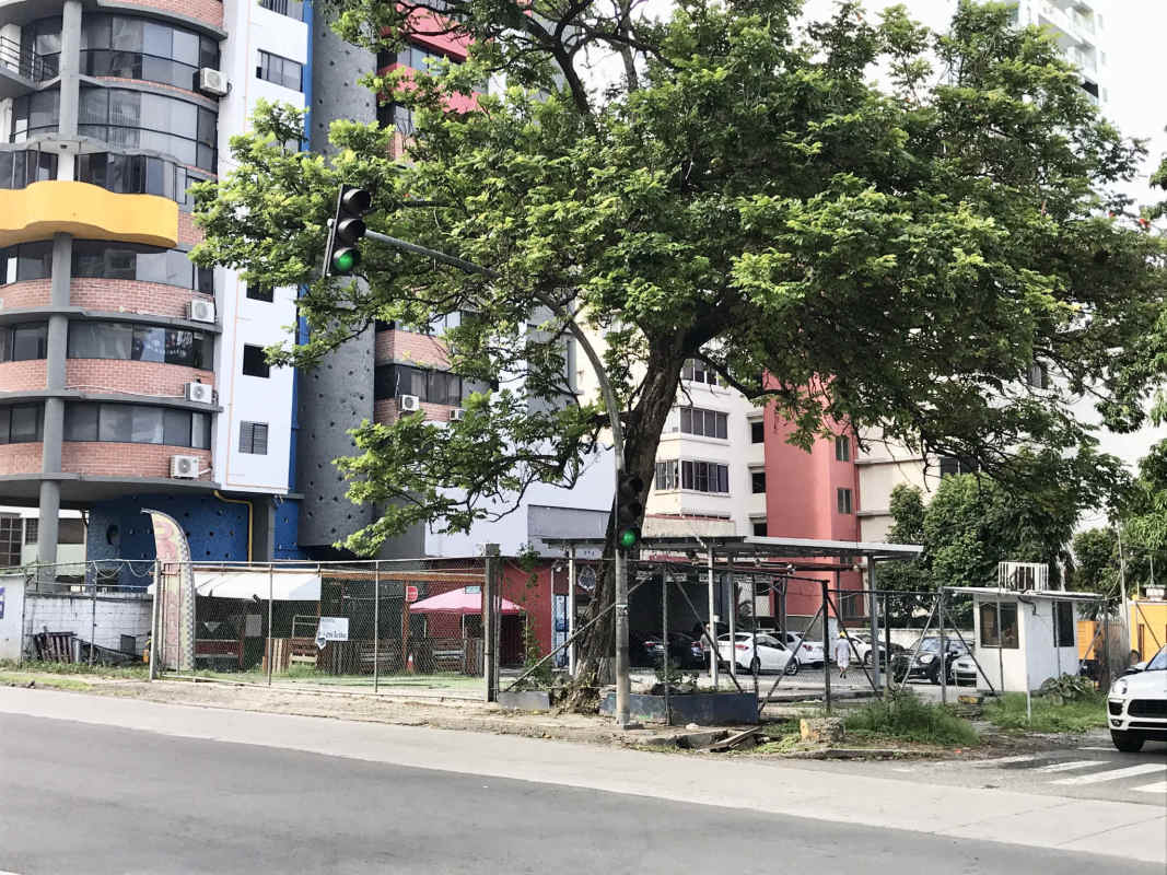 Urban street corner near high-rise buildings, fenced vacant lot Coco del Mar Panama City