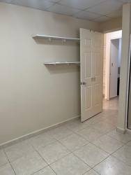 Bedroom with shelves, tile floor, and open door Arboledas Cluster Panama
