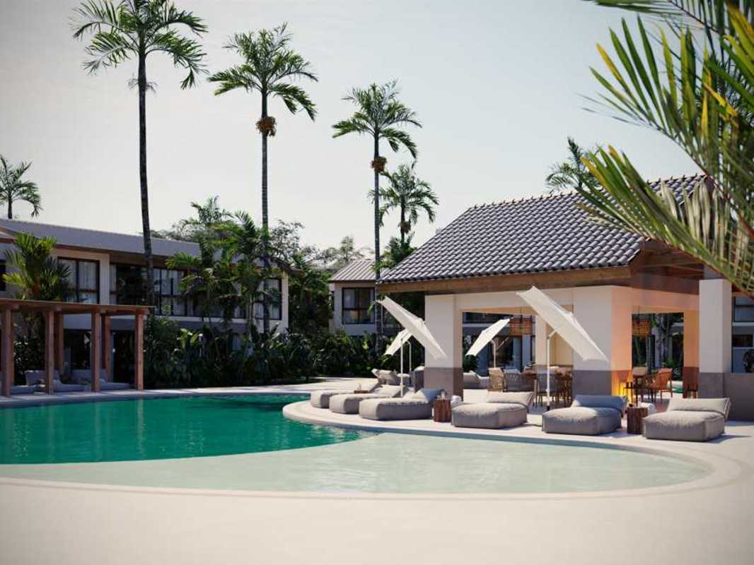 Swimming pool with lounge chairs, umbrellas, lush tropical garden in beachfront Playa Caracol Panama