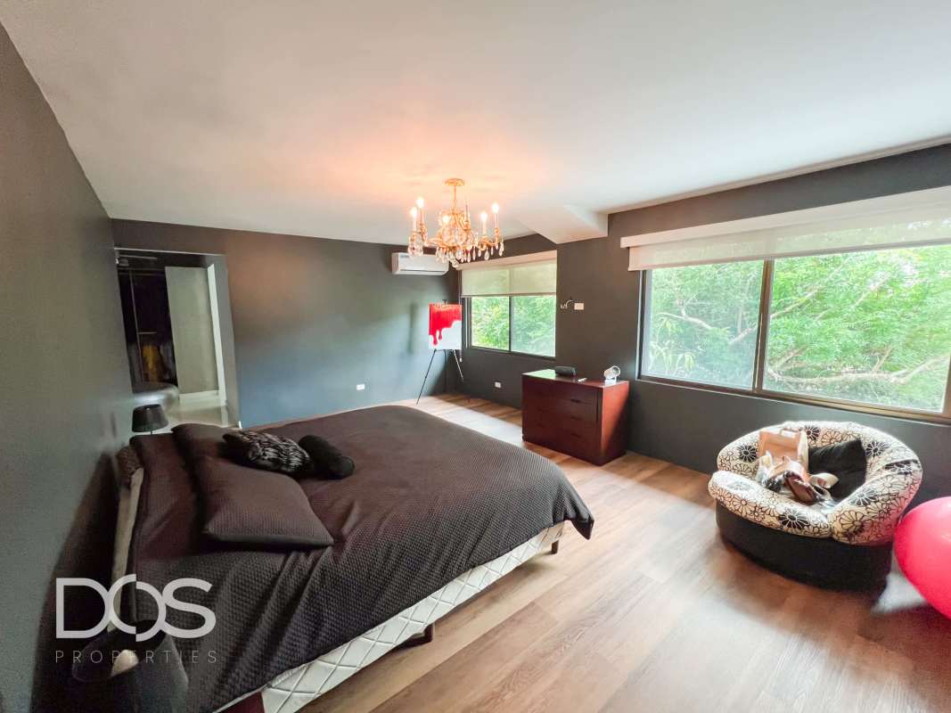 Minimalist bedroom with twin beds, large window, AC, and wood floors in remodeled Clayton residence