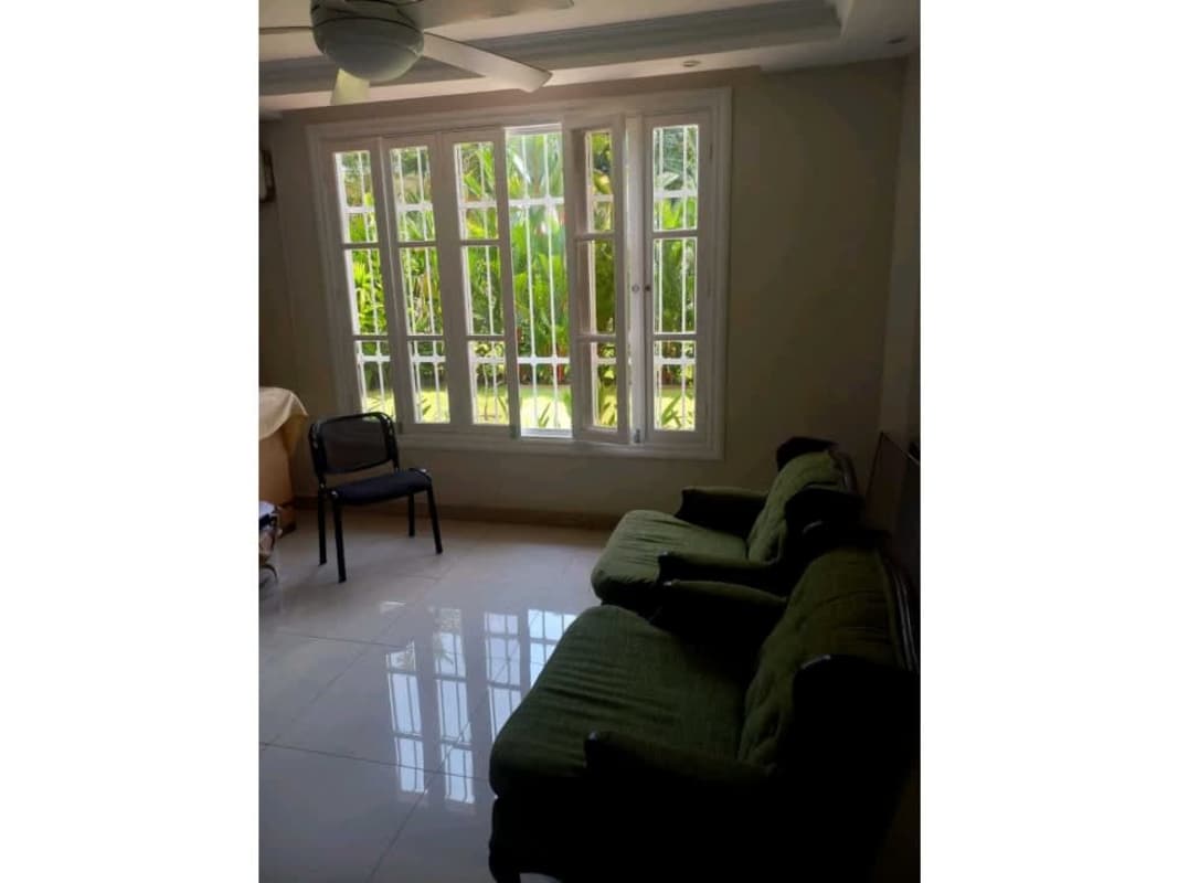 Living room green sofa, large window overlooking garden Ancon rental house Panama