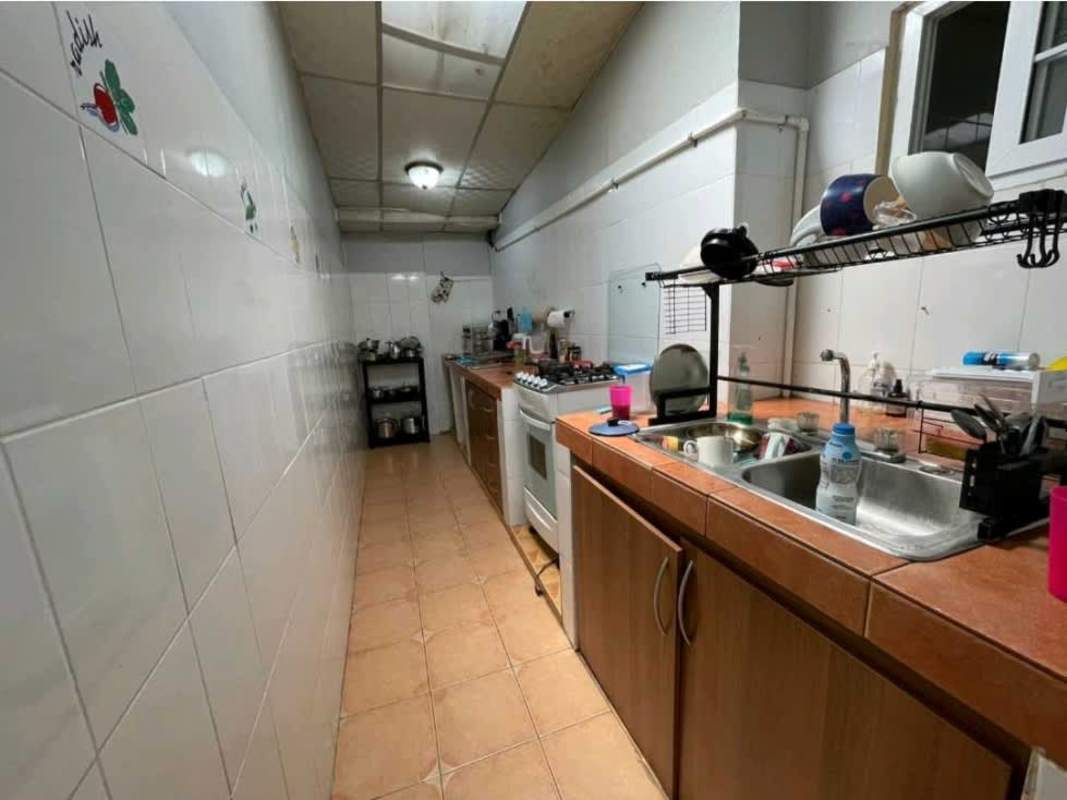 Narrow galley kitchen with tiled walls, cabinets and stove in multifamily property Rufina Alfaro Panama