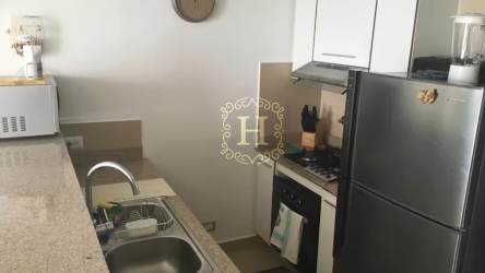 Compact modern kitchen with granite countertop, appliances, and cabinetry in El Palmar beachfront condo Panama