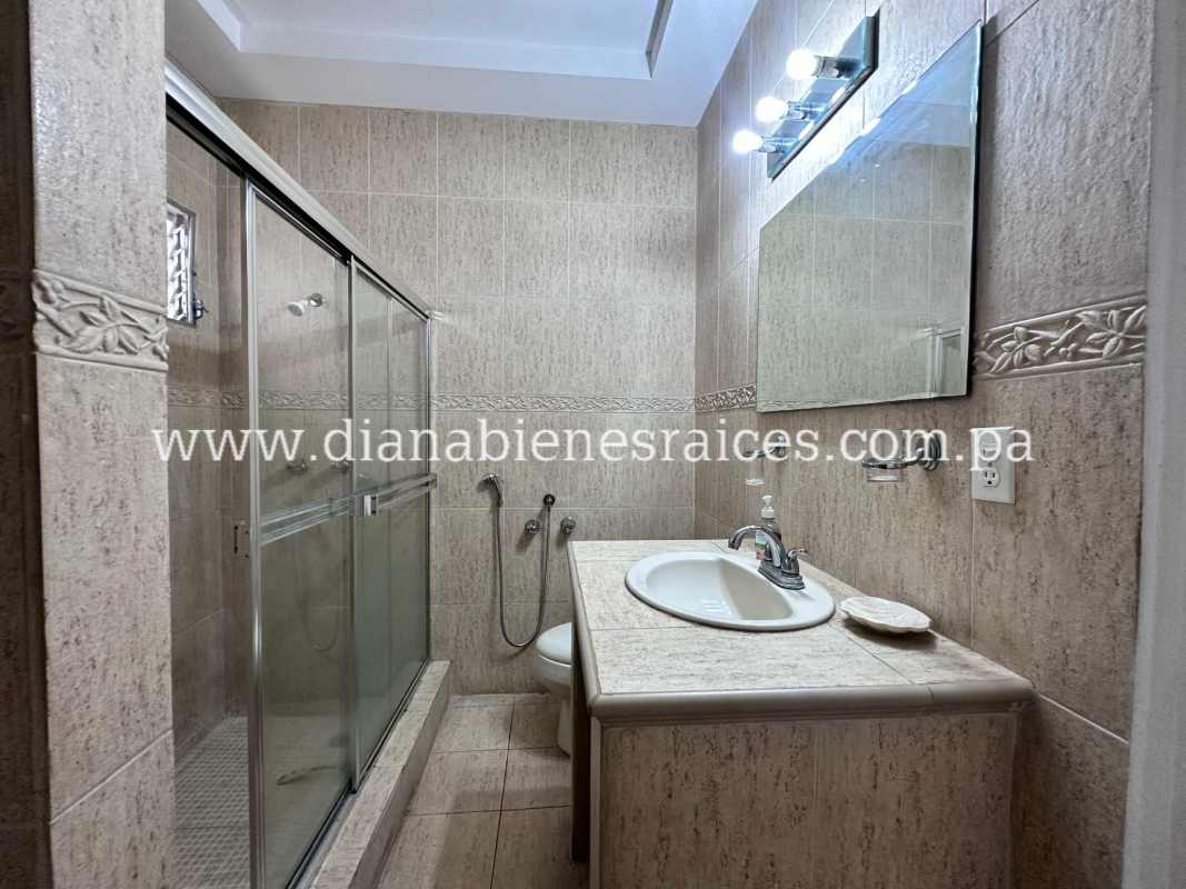 Bathroom with beige tile, glass shower enclosure, large mirror in Villas de las Fuentes Panama house