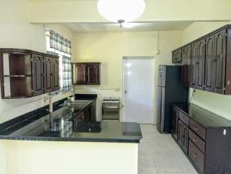 Kitchen with wood cabinets, granite counters, fridge inside Residencial Howard duplex Panama