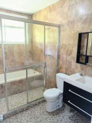 Beige tiled modern bathroom with vanity, glass shower in Residencial Howard Panama