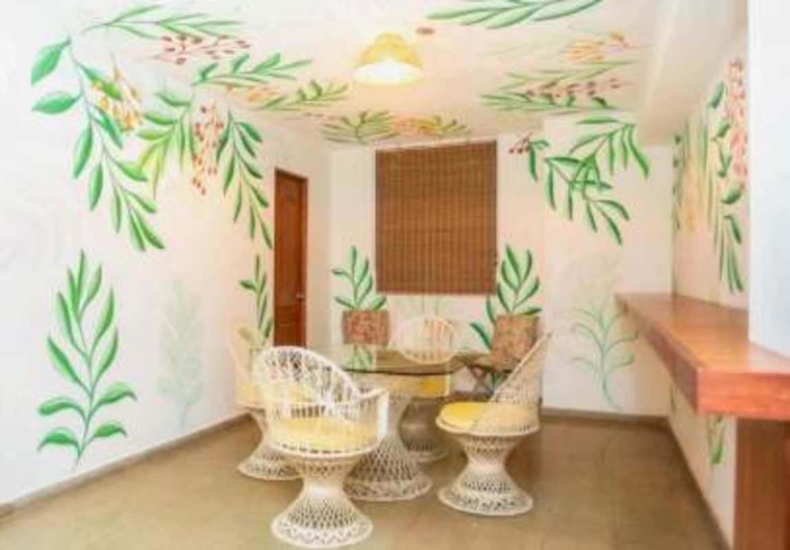 Indoor dining area with glass table, wicker chairs, tropical murals Restaurant Hotel Panama