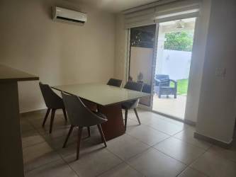 Open living room with sofas, TV wall, staircase in Bosques del Pacífico home Panama Pacífico