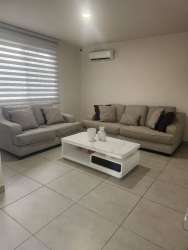 Modern dining room with glass table, gray chairs and garden view in Bosques del Pacífico