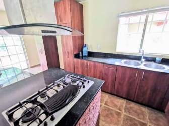 Modern kitchen with granite tops, gas stove, wood cabinets Panama Pacifico Villas de Howard