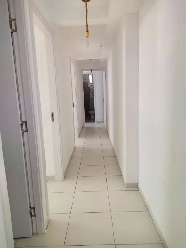 Minimalist corridor with ceramic tiles connecting apartment rooms in PH El Crisol Panama