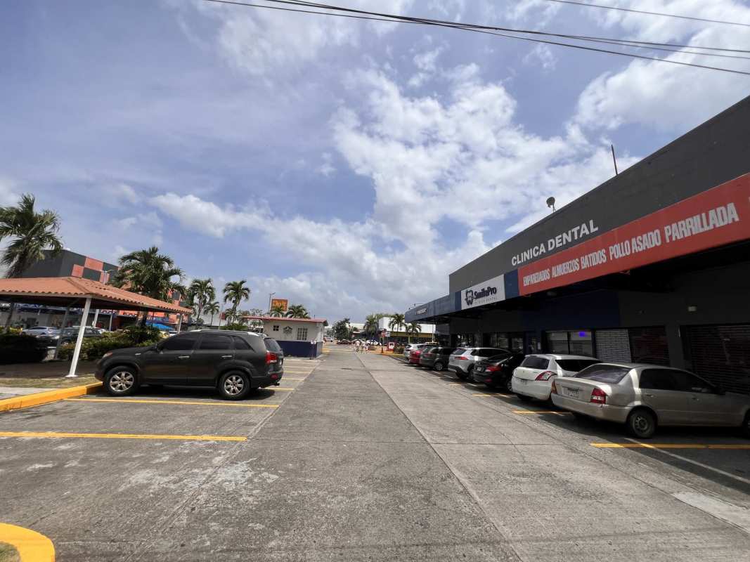 Commercial center with parking lot, palm trees and visible storefront signage at Los Pueblos Panama City