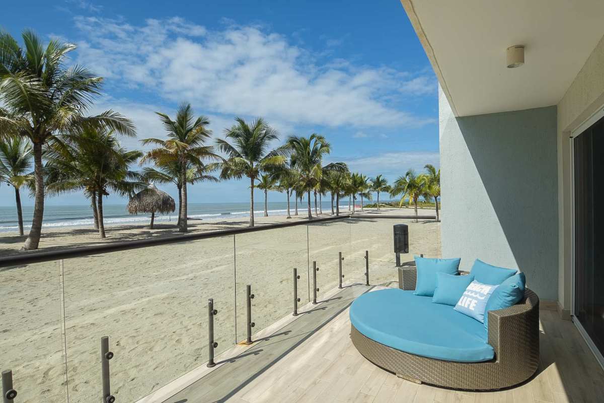 Private oceanview balcony with wicker lounge chair and tropical palm views at Playa Caracol Punta Chame