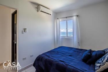Bedroom featuring navy bedding, AC, window with ocean view in Las Olas Tower Playa Barqueta Panama