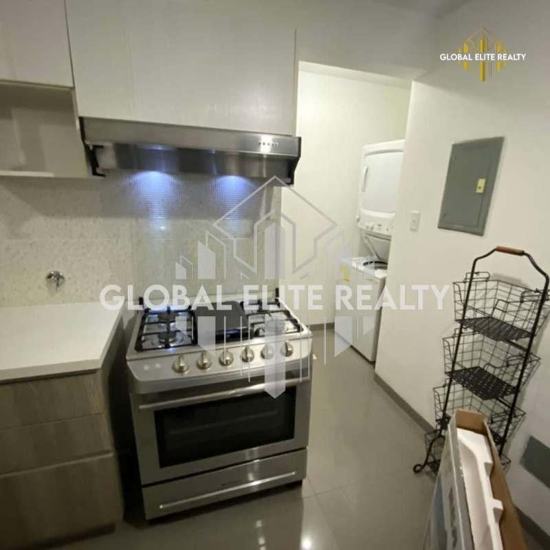 Kitchen with gas stove, range hood and adjacent laundry stacked washer dryer in PH La Riviera Pedregal Panama