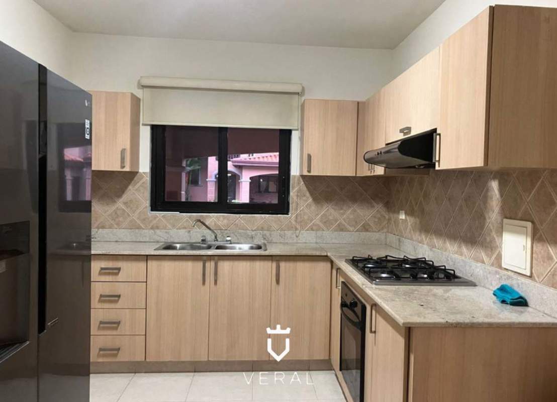 Kitchen with wood cabinetry, granite countertops, gas stove, large window in duplex Versalles Panama