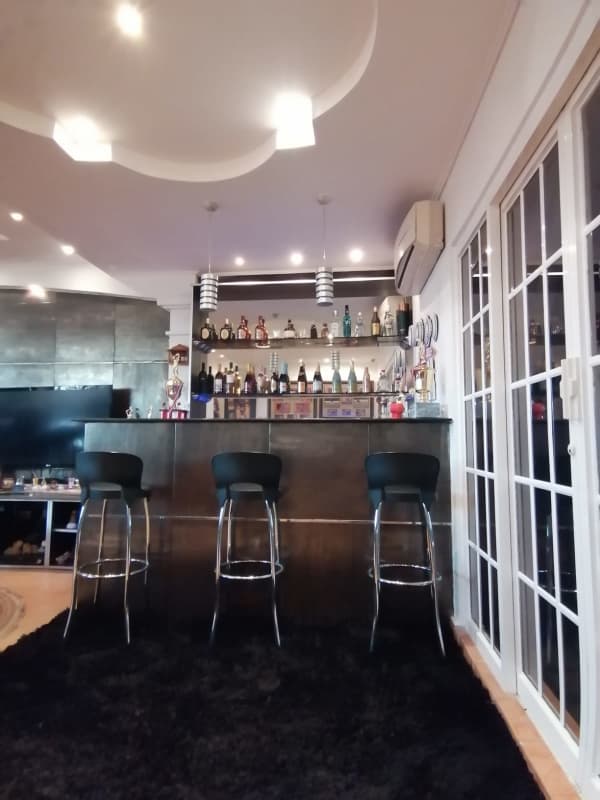 Bar corner with black stools, mirrored shelving, pendant lights in house for sale Panama