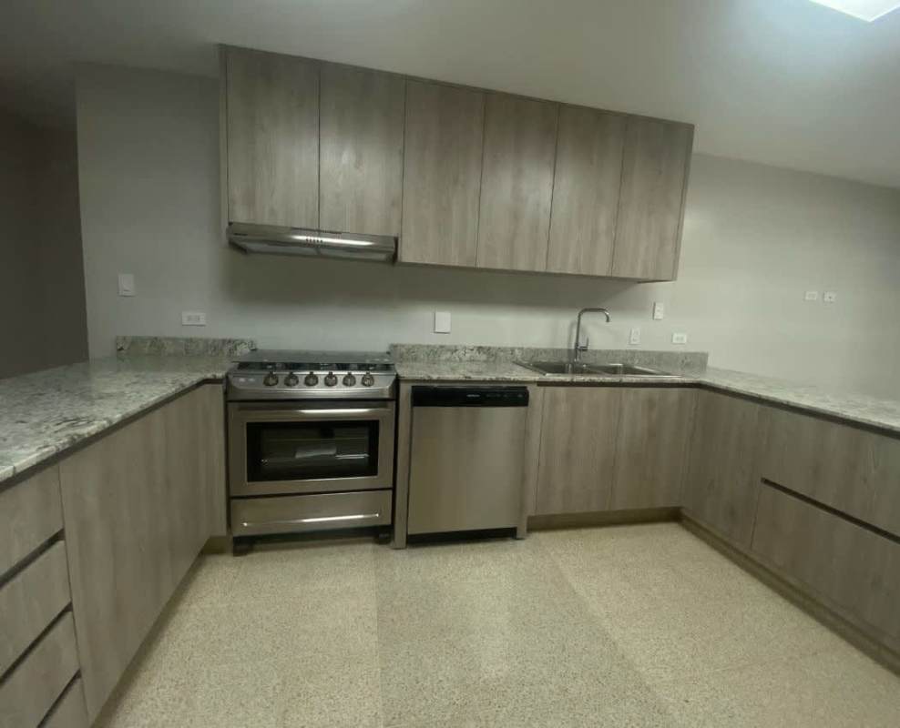 Large modern kitchen with granite countertops, wooden cabinets, stainless steel appliances in Altos del Golf Panama luxury house