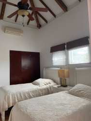 Master bedroom with exposed beams ceiling, ceiling fan, two beds in Costa Blanca golf beach home Panama