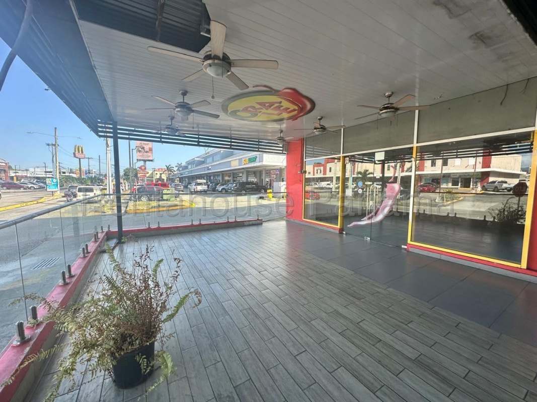 Covered outdoor terrace with glass railings and seating at Brisas Mall Panama