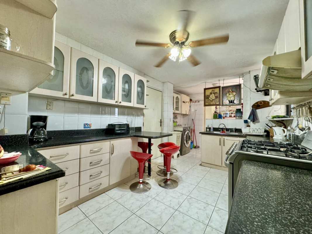 Traditional kitchen with granite counters breakfast bar red stools PH Terrazas de Obarrio Panama City