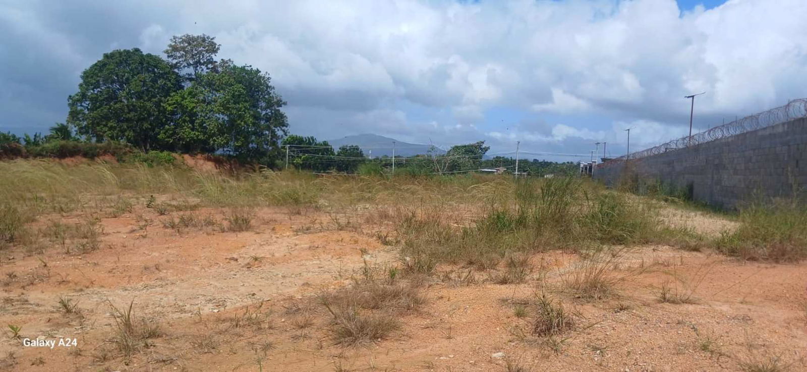 Vacant plot near boundary wall and utility poles along highway in Pacora Panama City