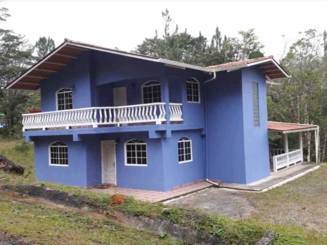 Exterior of blue mountain house with balcony, balustrade, covered patio in Cerro Azul Panama
