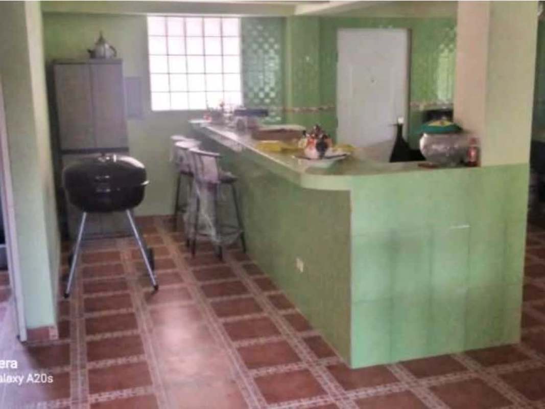 Traditional kitchen with tiled countertop, green tile walls, breakfast bar and stools in Cerro Azul mountain house Panama
