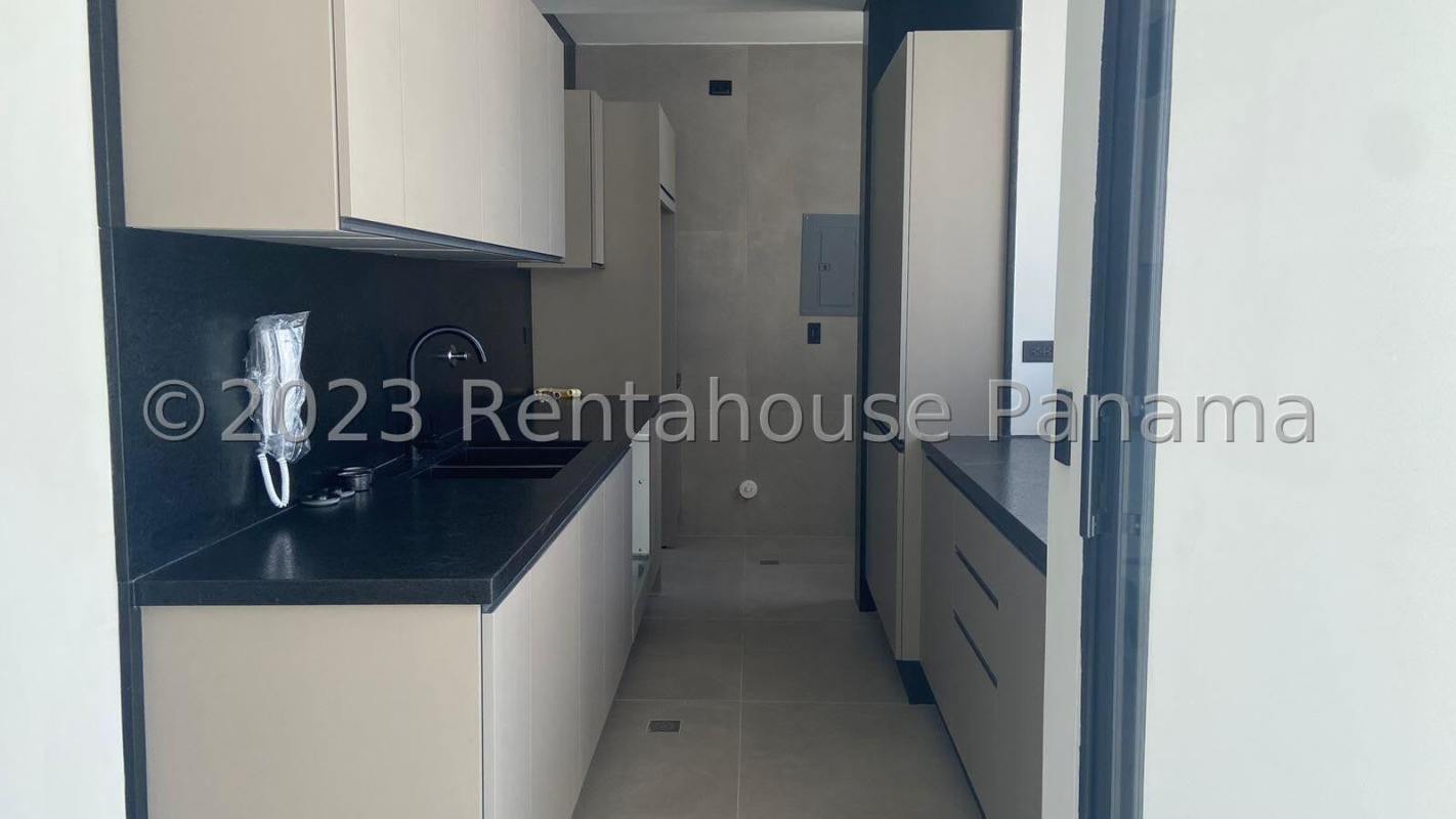 Sleek galley kitchen with black countertops, beige cabinets in PH Victory Wellness Panama