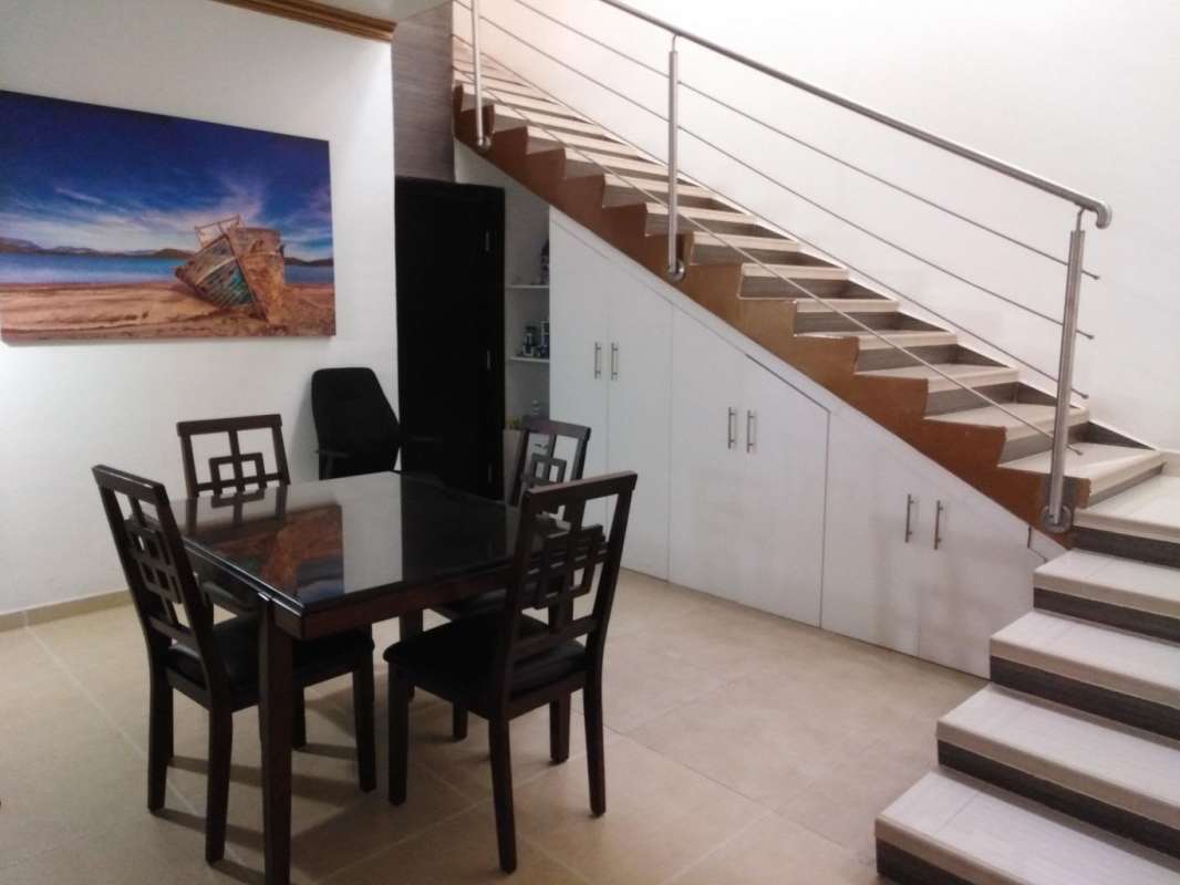 Dining area with glass table and metal railed staircase in Altos de Panamá