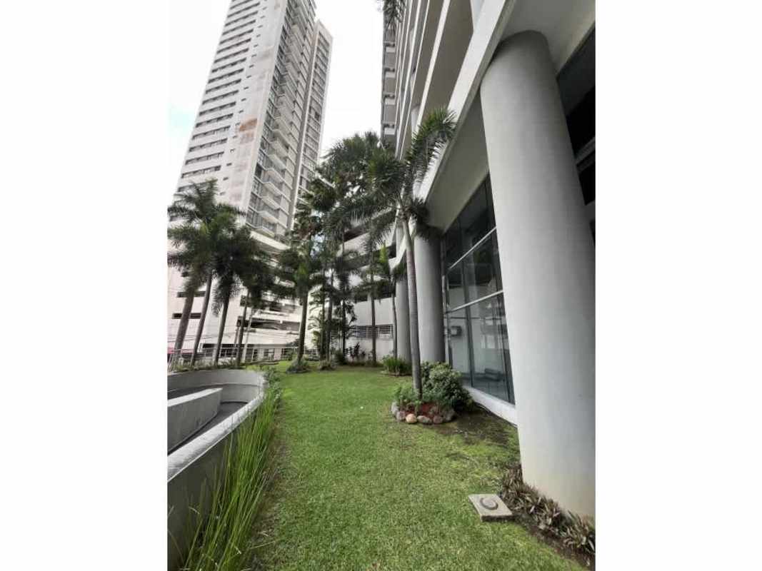 Entrance of PH Luxor 100 with glass facade, palm trees, gardens, El Cangrejo Panama City