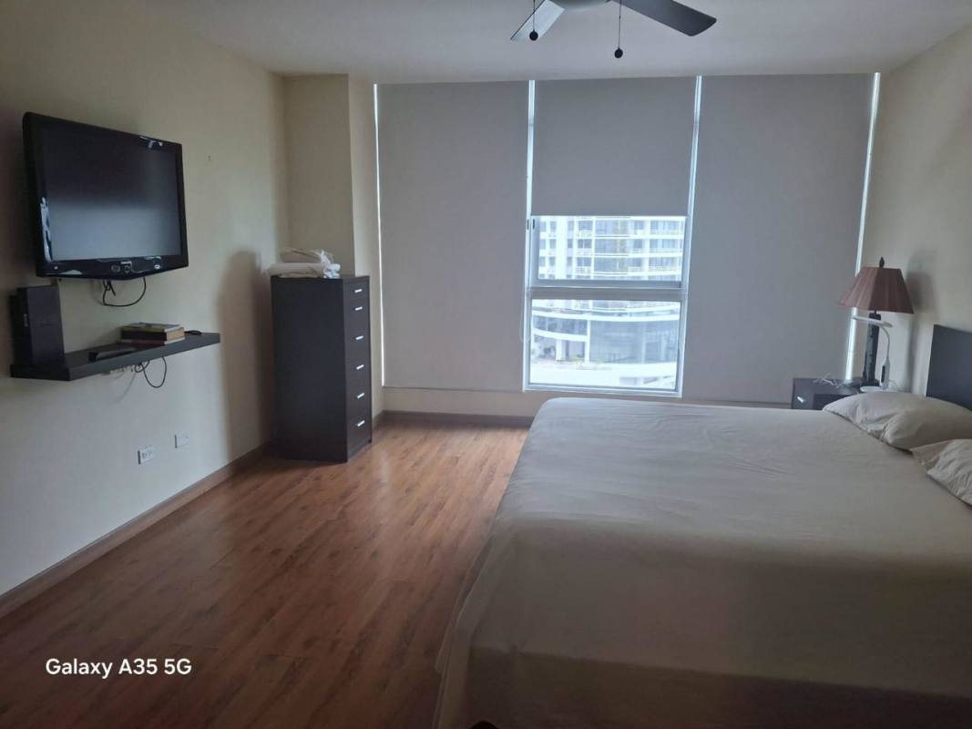 Large bedroom with king bed, closet, TV, and city skyline view in PH Bayfront Tower Panama