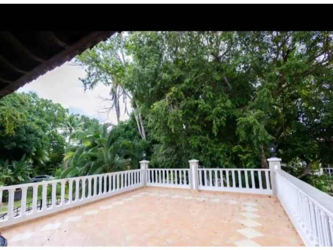 Large outdoor terrace with tiles, garden view, and white balustrade at diplomatic mansion