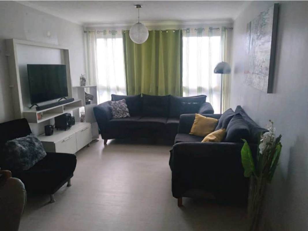 Modern living room, black sofas, green curtains, wall shelves at PH Bosque del Castilla Río Abajo Panama City