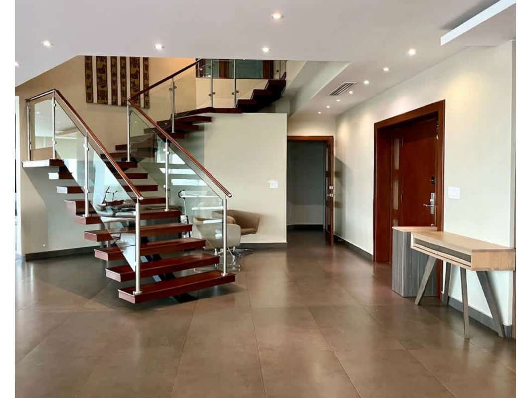 Elegant open stairway with glass railing connecting levels of PH Vista Park luxury penthouse Panama