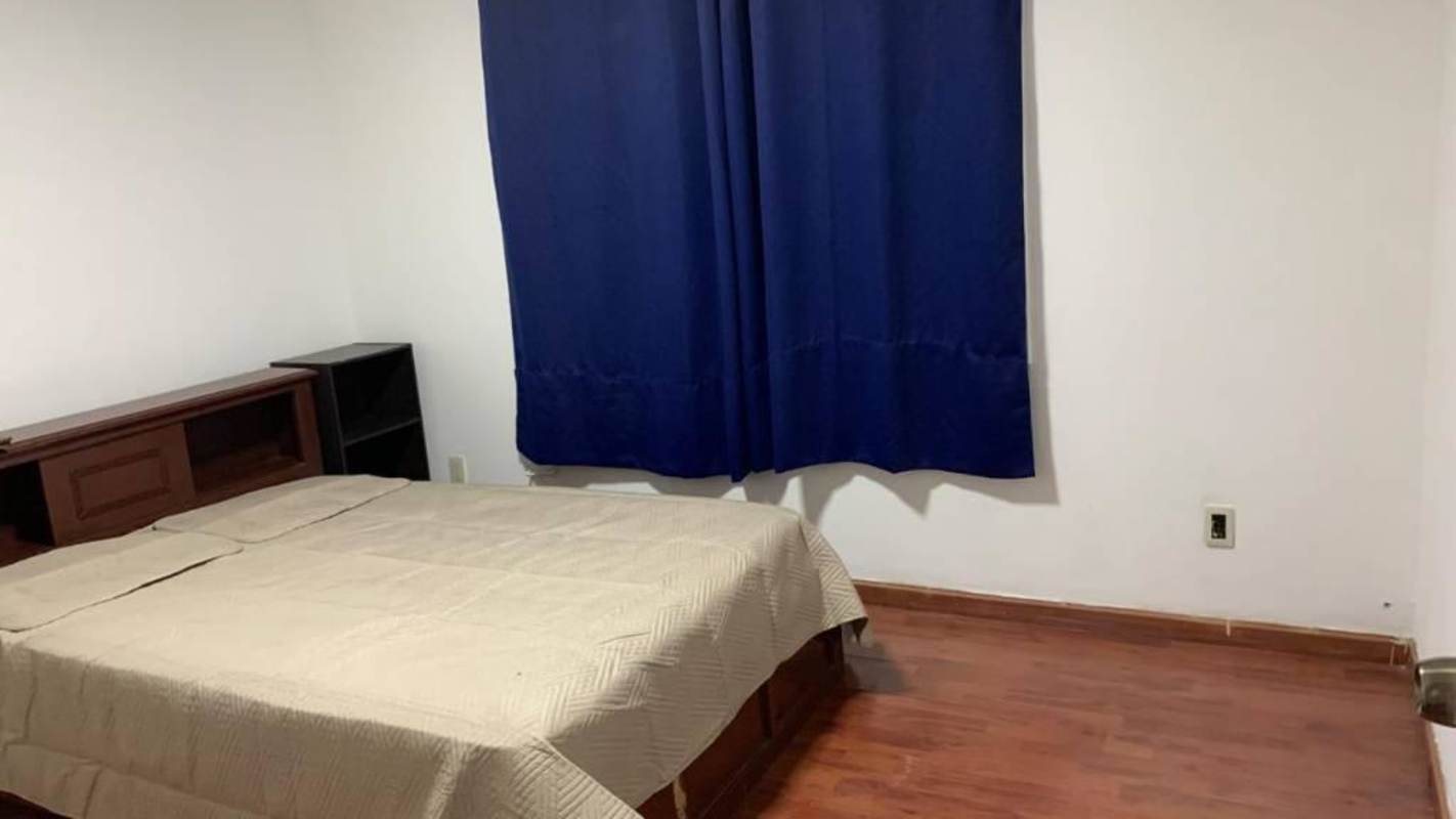 Bedroom with wooden floors bed blue curtains minimal design Clayton Panama apartment