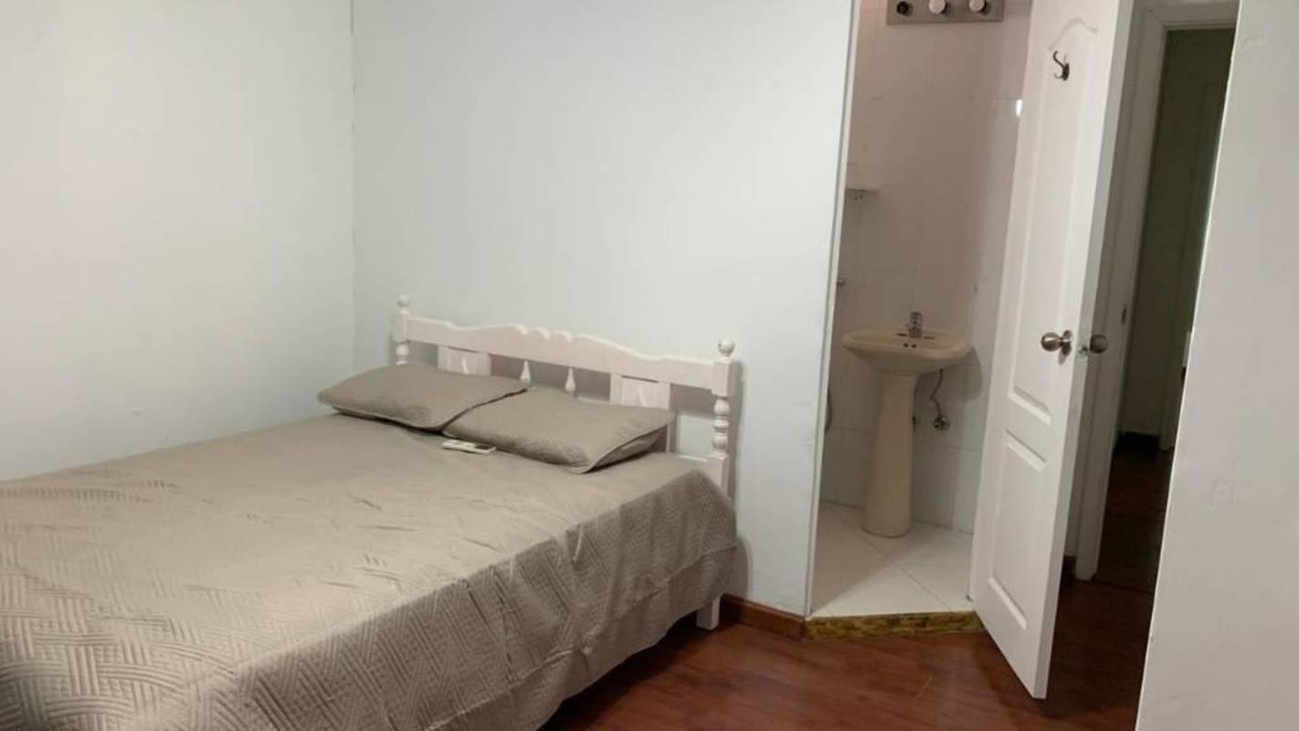 Bedroom with ensuite bathroom beige bedding wooden floors Clayton Panama furnished apartment