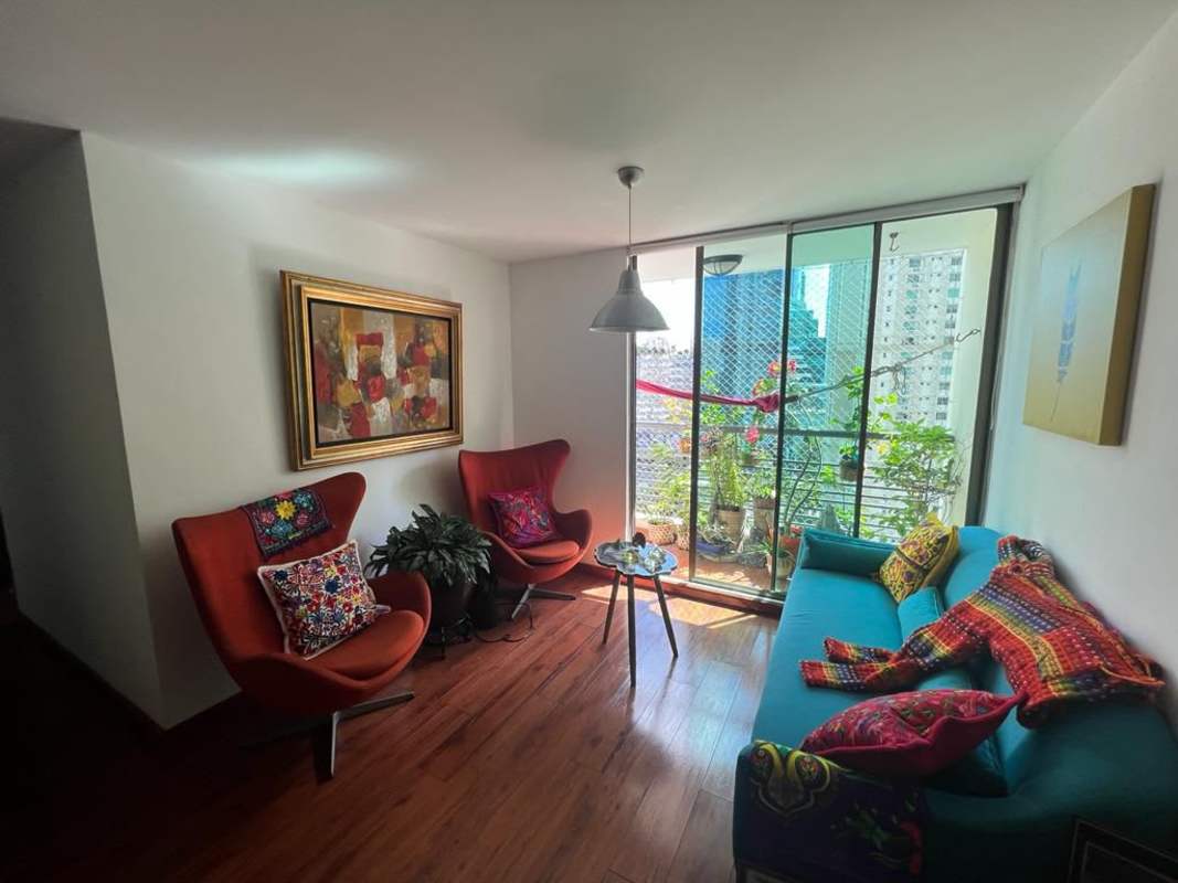 Modern kitchen with stainless steel refrigerator, wood cabinetry, black countertop in PH Pacifica Park Panama