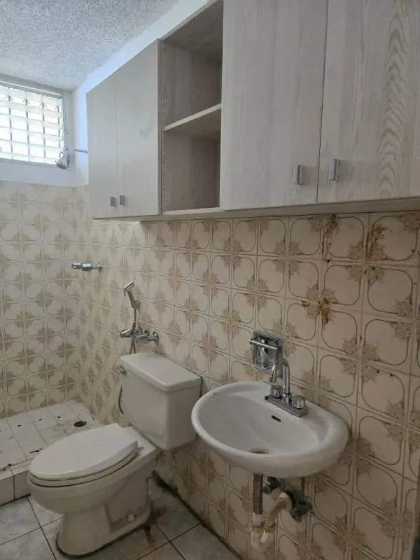 Vintage bathroom with patterned tiles, wall-mounted cabinets, toilet and sink in PH La Alameda Villa de las Fuentes Panama