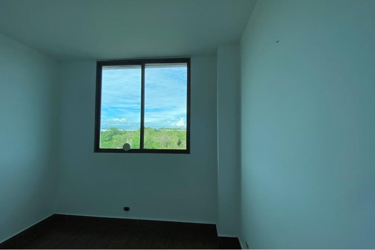 Modern minimalist bedroom with large window overlooking gardens in Costa Sur Village Panama