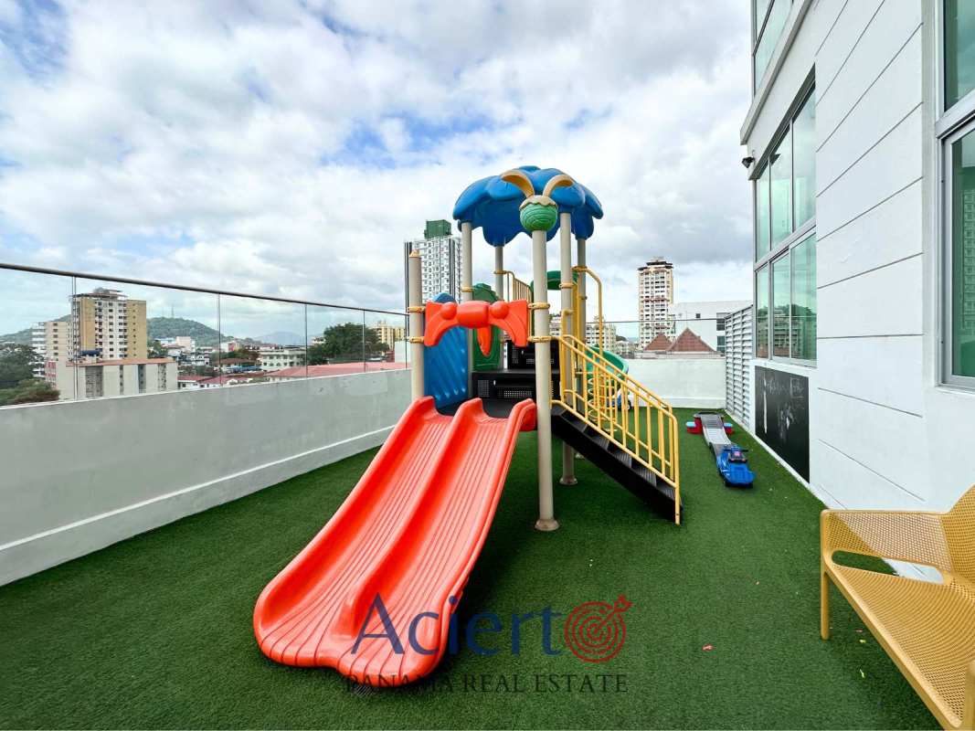Children's playground with slides and skyline backdrop on rooftop of Bella Vista Park Panama City