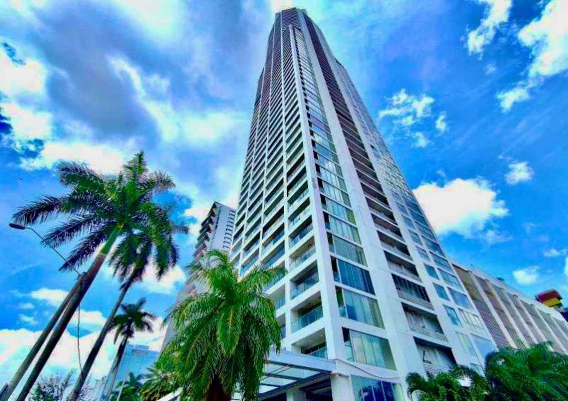 Iconic modern high-rise glass facade of PH Rivage Tower on Avenida Balboa with palm trees