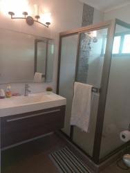 Bathroom with glass shower, wall vanity, mirror in Club Ecuestre Coronado rental house