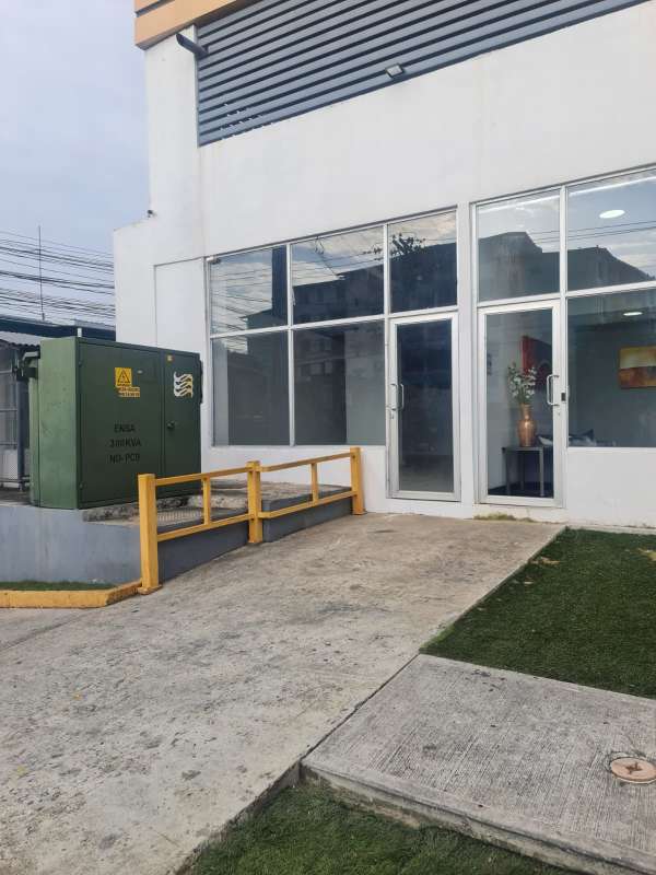 Modern exterior of commercial building with glass doors, handicap ramp and green transformer box in Parque Lefevre Panama