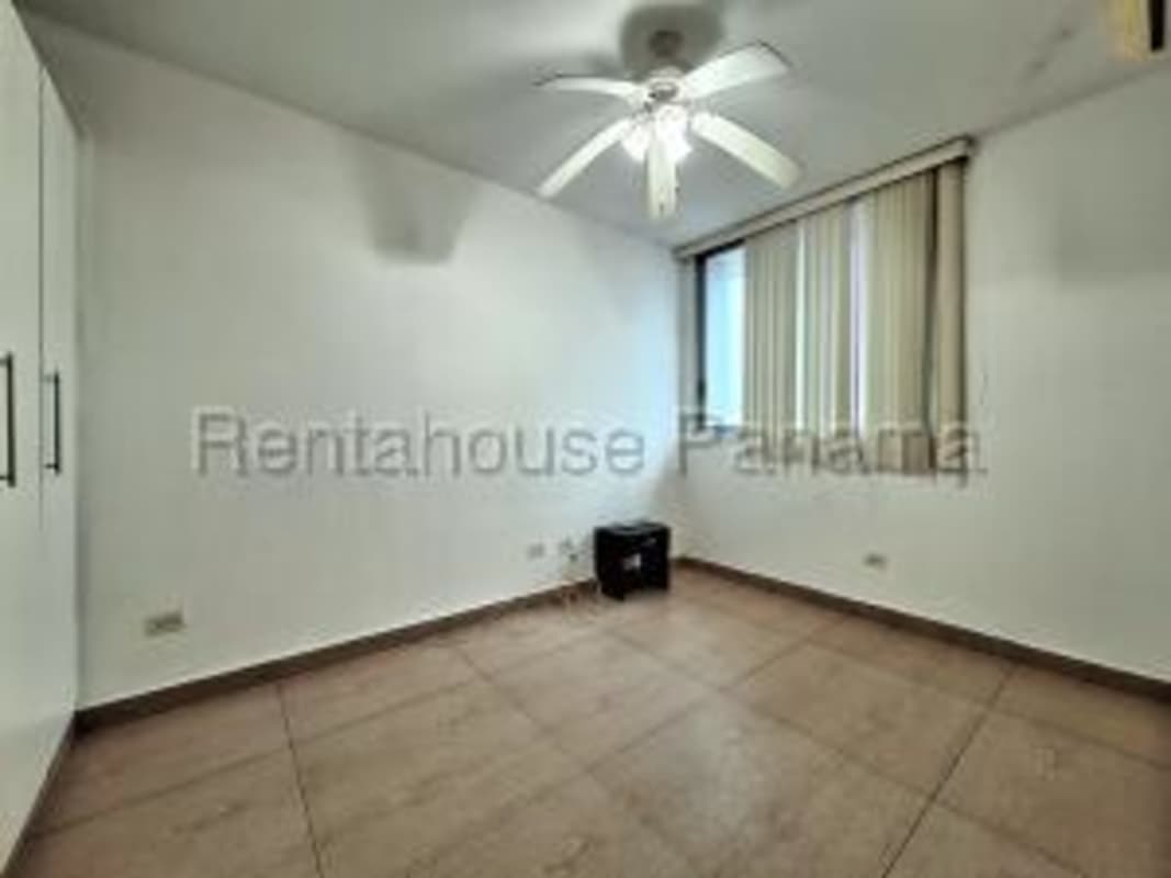 Master bedroom with large windows offering partial ocean view and ample natural light
