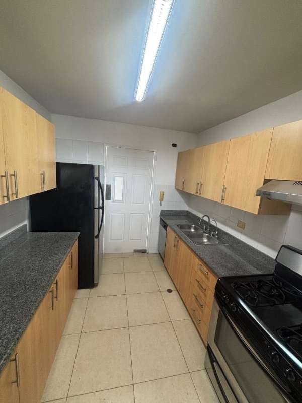 Modern kitchen with granite countertops, wood cabinets, stainless appliances at Costa del Este condo